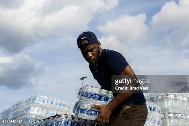 Jabari Omari, a City of Jackson employee, helps hand out cases of bottled water at a Mississippi Rapid Response Coalition distribution site on August...