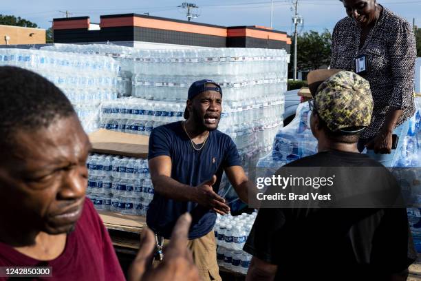 Jabari Omari, a Jackson city employee, talks with a resident while helping hand out cases of bottled water at a Mississippi Rapid Response Coalition...