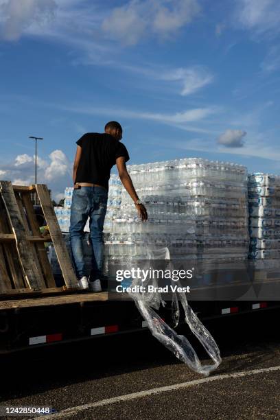 Dontavious Spann helps hand out cases of bottled water at a Mississippi Rapid Response Coalition distribution site on August 31, 2022 in Jackson,...