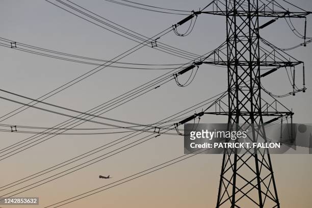 An aircraft takes off from Los Angeles International Airport behind electric power lines at sunset as the California Independent System Operator...
