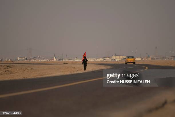 Photo taken on August 31, 2022 shows a pilgrim walking towards Karbala on the Iraqi side of the border with Iran near the Shalamjah crossing point,...