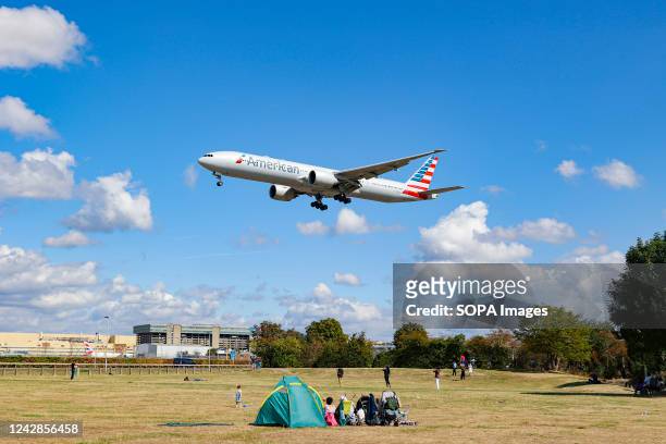Boeing 777-300ER aircraft of American Airlines arriving at London Heathrow Airport flying above the houses in Myrtle Ave, a famous location for...