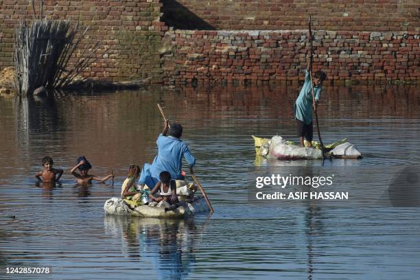 People use rafts to cross a flooded area after monsoon rains on the outskirts of Sukkur, Sindh province, on September 1, 2022. - Monsoon rains have...