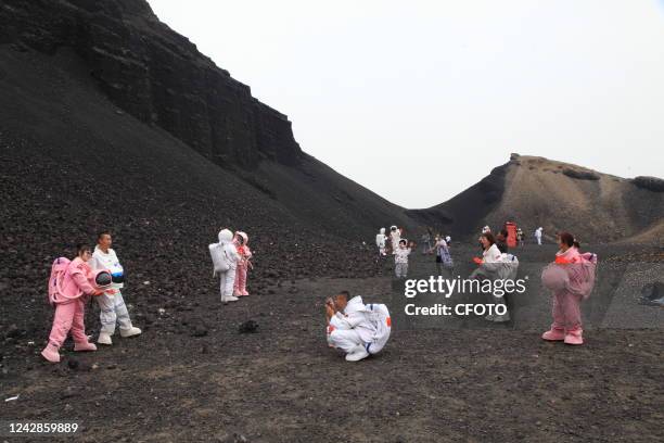 Tourists wearing spacesuits pose with national flags at Ulan Hada Volcanic Geological Park in Ulanqab, Inner Mongolia, China, July 27, 2022.