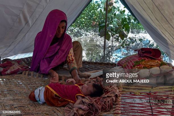Flood-affected Hajira Bibi sits with her child inside a tent near her flooded house at Jindi village in Charsadda district of Khyber Pakhtunkhwa on...