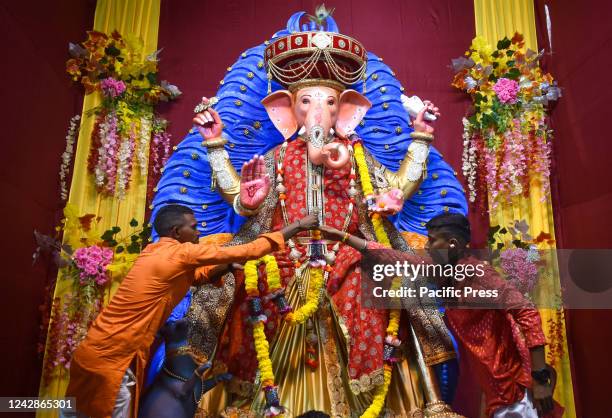 People are worshipping an idol of the Hindu god Ganesh, the deity of prosperity, inside a "pandal" a temporary makeshift tent on the first day of the...