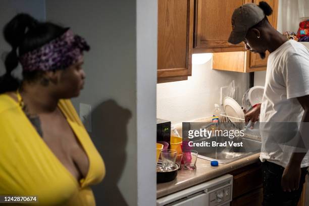 Jamiya Williams, left, watches as her fiance, Terrence Carter, right, pours bleach into the water before washing dishes in response to the water...