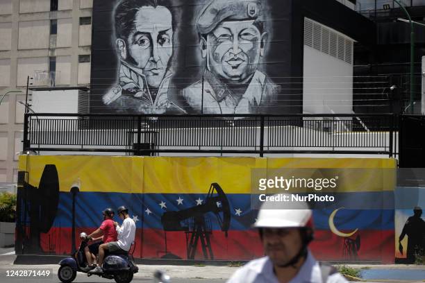 Motorcyclists walk past an oil-themed mural in Caracas, Venezuela on Sept. 01, 2022