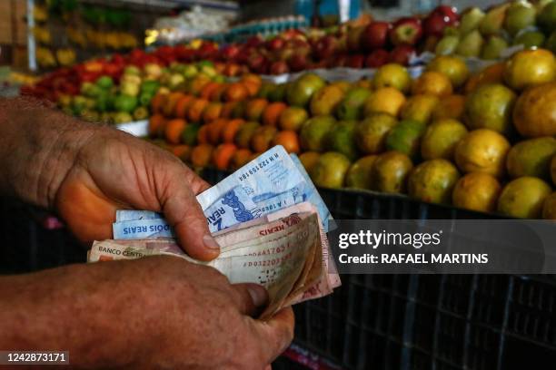 Customer counts money at a fruit and vegetables stall in a market in Salvador, Bahia State, Brazil, on August 26, 2022. - A majority of Brazilians...