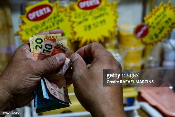 Customer counts money at a market in Salvador, Bahia State, Brazil, on August 26, 2022. - A majority of Brazilians will be thinking of their pockets...