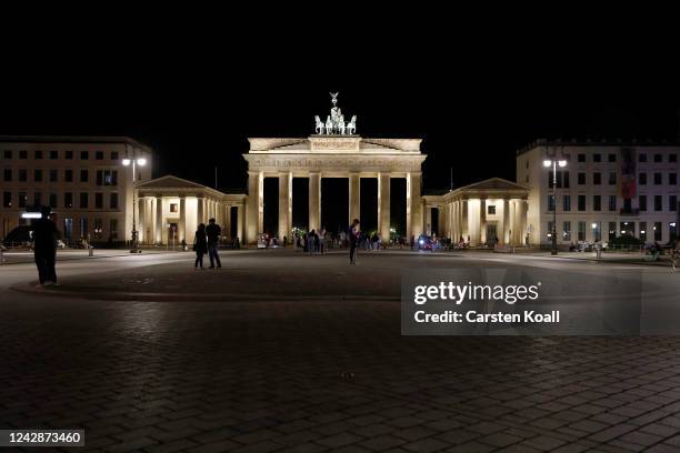 People walk among the iluminated Brandenburg Gate, one of Berlin's premiere landmarks, on the first day a new law to save energy nationwide has gone...