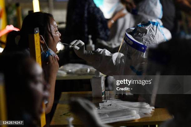 This photo taken on September 1, 2022 shows a health worker taking a swab sample from a resident to test for the Covid-19 coronavirus in Chengdu, in...