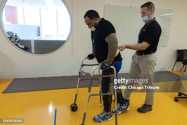 Lemuel Johns uses a hydraulic brace to practice walking with Physical Therapist Matt McGuire in the Technology Innovation Hub at the Shirley Ryan...