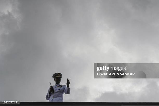 An Indian Navy officer gestures from a deck of the Indian indigenous aircraft carrier INS Vikrant during its commissioning at Cochin Shipyard in...