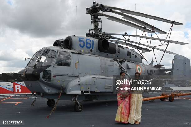 Women stand next to Komoho Helicopter on the deck of the Indian indigenous aircraft carrier INS Vikrant during its commissioning at Cochin Shipyard...
