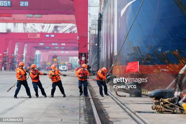 Dock workers pull the mooring line of a cargo ship at Qingdao Port on June 2, 2020 in Qingdao, Shandong Province of China.