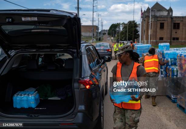 Member of the National Guard places a case of water in the back of a car at the State Fair Grounds in Jackson, Mississippi, on September 2, 2022. -...