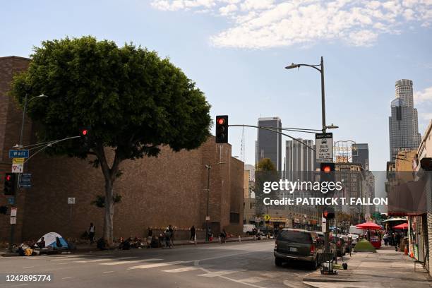 People camp in tents under a shady tree on the sidewalk near Skid Row during a heat wave in downtown Los Angeles, California on September 2, 2022. -...