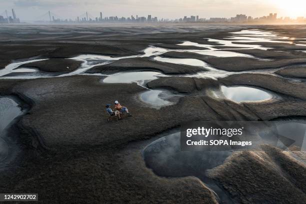 Two women sit on the exposed banks due to low water levels caused by drought, along the Yangtze River. China has been hit by its most severe heatwave...