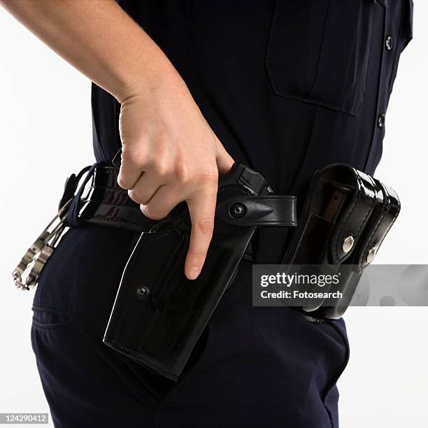 close up side view of mid adult female caucasian law enforcement officer hand on gun in holster. - holster stock pictures, royalty-free photos & images