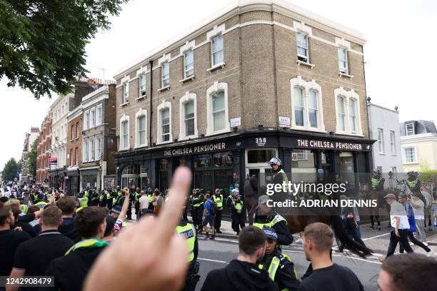 West Ham United's fans gesture as they walk past The Chelsea Pensioner pub escorted by police officers on their way to attend the English Premier...