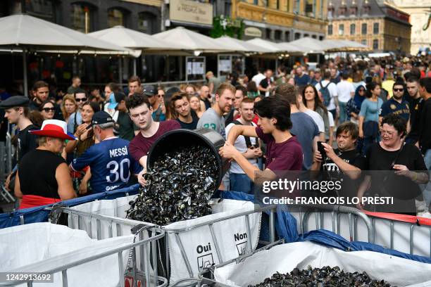 Employees of a restaurant empty a bucket of empty mussel shells onto a pile during the Braderie de Lille Flea Market, in Lille, northern France on...