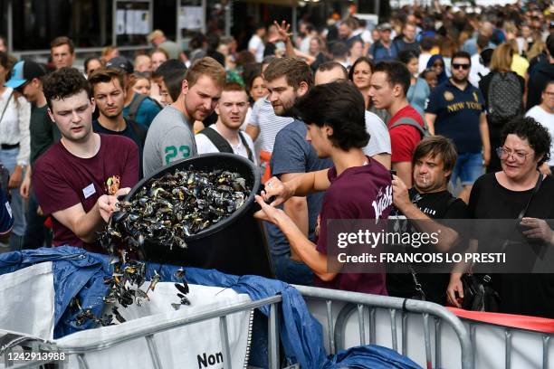 Employees of a restaurant empty a bucket of empty mussel shells onto a pile during the Braderie de Lille Flea Market, in Lille, northern France on...