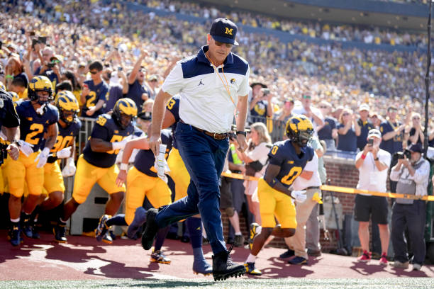 Head coach Jim Harbaugh of the Michigan Wolverines takes the field with his players before the first half against the Colorado State Rams at Michigan...