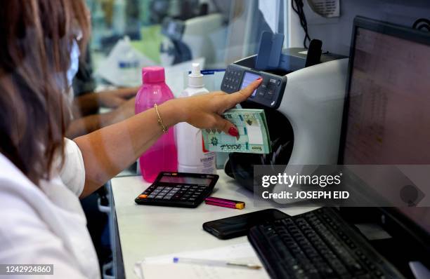 An employee counts cash for a customer at a money transfer office in Lebanon's capital Beirut, on July 27, 2022. - Transfer agencies are filling the...