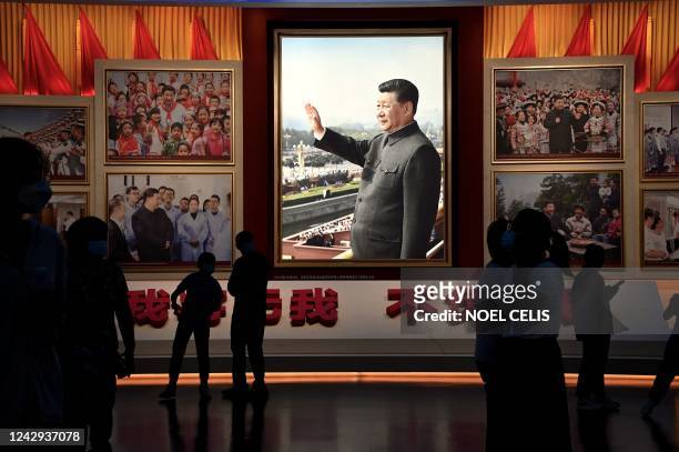 People stand in front of images of Chinese President Xi Jinping at the Museum of the Communist Party of China in Beijing on September 4, 2022.