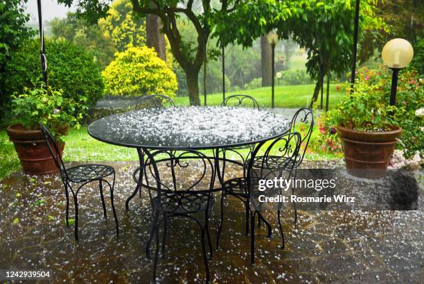 patio with garden furniture under heavy hailstorm - hail foto e immagini stock