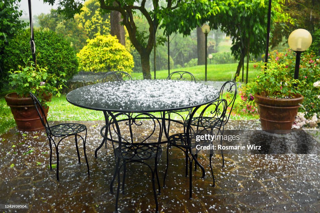 Patio with garden furniture under heavy hailstorm