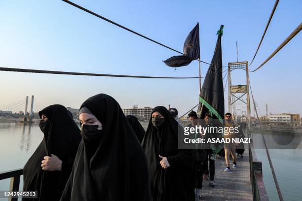 Shiite Muslim women pilgrims cross a pedestrian bridge across the Euphrates river as they march en route to Karbala from Nasiriyah in Iraq's southern...