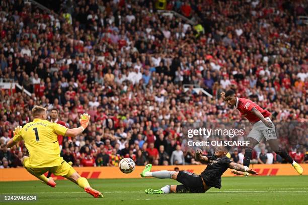 Manchester United's English striker Marcus Rashford shoots past Arsenal's English defender Ben White and Arsenal's English goalkeeper Aarron Ramsdale...