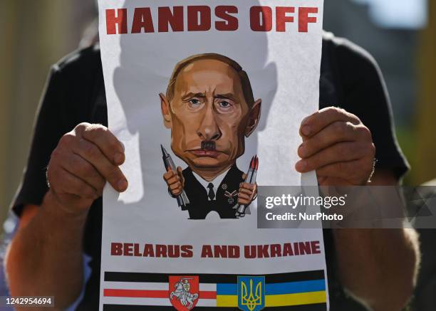 Protester holds a poster with an image of Russian President, Vladimir Putin and words 'Hands Off Belarus And Ukraine'. Members of the local...