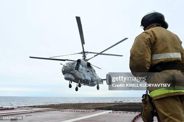 Russian Ka-27PL military helicopter flies over the deck of the Marshal Shaposhnikov anti-submarine destroyer during the 'Vostok-2022' military...