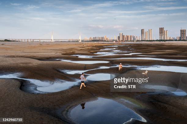 This photo taken on September 2, 2022 shows people walking on a section of a parched river bed along the Yangtze River in Wuhan in China's central...