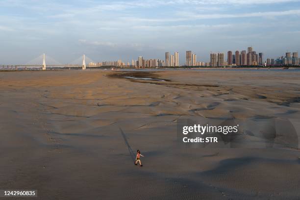 This photo taken on September 2, 2022 shows a man walking on a section of a parched river bed along the Yangtze River in Wuhan in China's central...