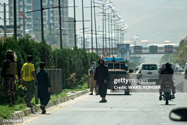 Taliban fighters stand guard along a road near the Russian embassy after a suicide attack in Kabul on September 5, 2022. - A suicide bomber struck...