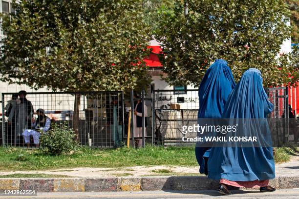 Afghan burqa-clad women walk past the Russian embassy after a suicide attack in Kabul on September 5, 2022. - A suicide bomber struck near the...