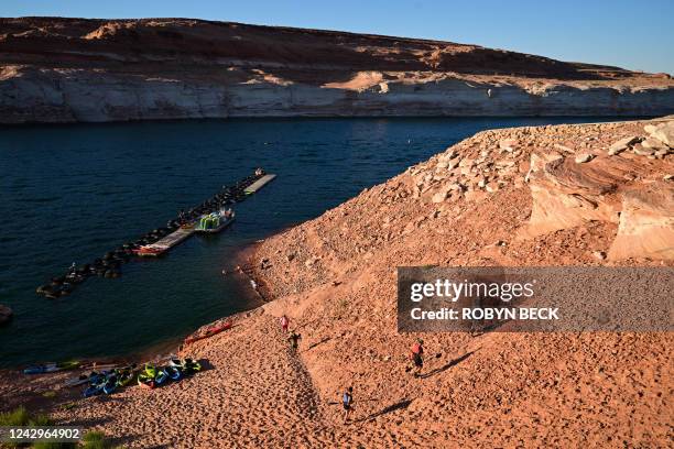 Kayakers walk up a steep, rocky incline to exit the water due to low water levels in Lake Powell, at the Antelope Point Boat Ramp in Page, Arizona,...