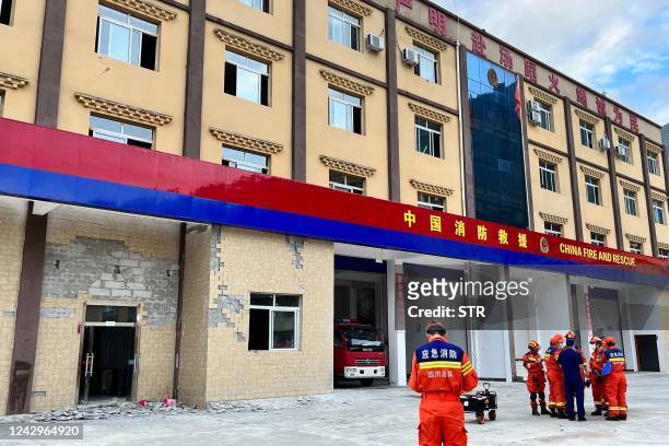 Firefighters gather near a damaged wall of a fire station after a 6.6-magnitude earthquake in Hailuogou in China's southwestern Sichuan province on...