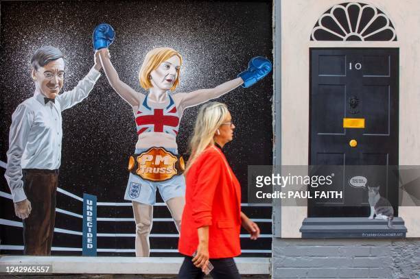 Woman walks past a mural painting in Belfast city centre, made by artist Ciaran Gallagher and depicting as boxer British Foreign Secretary Liz Truss...