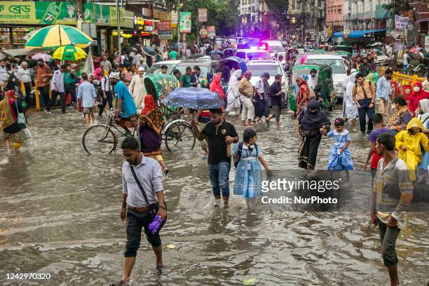 Children cross road after school through the waterlogged streets after heavy rainfalls in Dhaka, Bangladesh on September 05, 2022. After heavy...