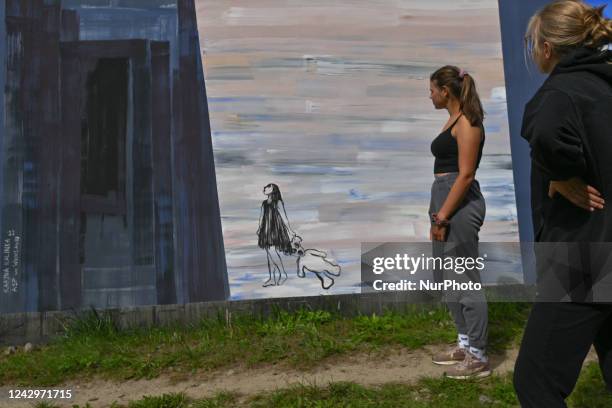 Two young women look at a mural in relation to Russian invassion to Ukraine, created by a young artist karyna Kalinka. More than 25 anti-war and...