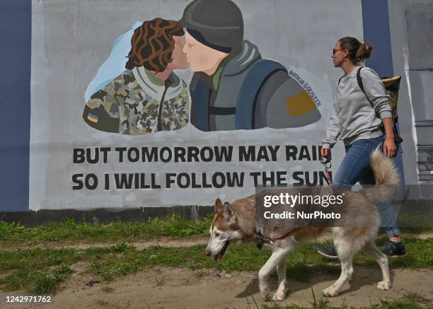 Young woman with a dog walks by at a pro-Ukrainian mural created by a young artist Natalia Goliszek. More than 25 anti-war and pro-Ukrainian murals...