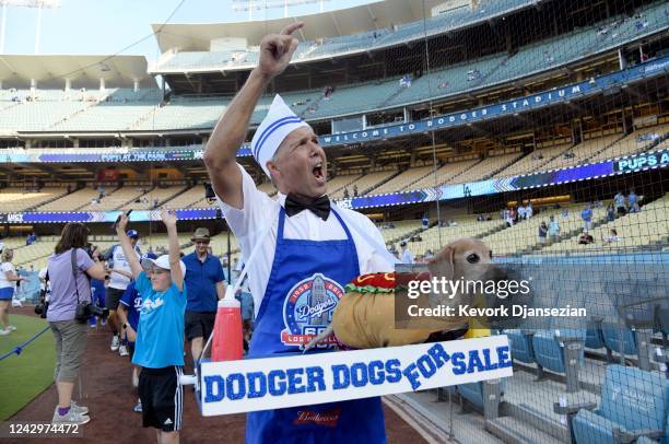 Roger Swift yells "who wants a Dodger Dog" as he walks around the baseball field with his dashund during the Pups at the Park Parade presented by...