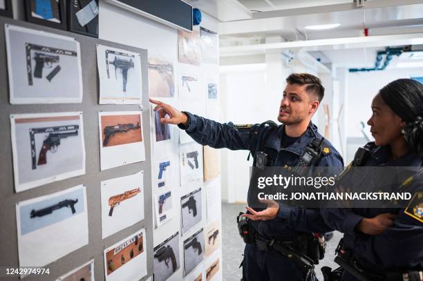 Police officers Michael Cojocaru and Rissa Seidou point on a board showing images of ceased weapons in Rinkeby police station on August 31, 2022 in...