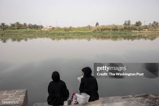 Two women are studying by the Tigris River in Basra, Iraq, on August 18, 2022.