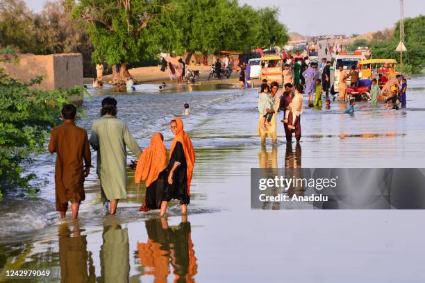 People wade through a flooded area in Sewan Sharif, southern Sindh province, Pakistan on September 06, 2022. Monsoon rains and melting glaciers in...